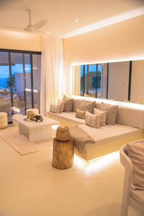 Una sala de estar moderna con un sofá grande, una mesa de centro y un taburete de madera decorativo.