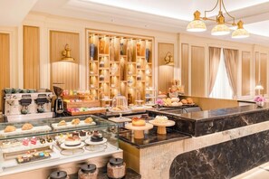 Un vestíbulo de hotel con una recepción de mármol, una pared con botellas ordenadas y una máquina de café.