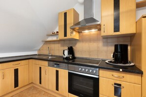 Eine Küche mit Holzschränken, einer schwarzen Arbeitsplatte, einer Kaffeemaschine und einem Backofen.