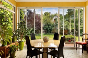 A dining area with a table, chairs, and potted plants.
