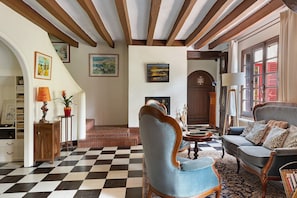 A checkered floor, wooden furniture, a fireplace, and a clock on the wall.