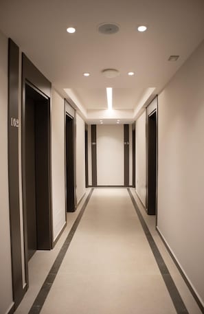 A hotel hallway with doors numbered 102, 104, and 105, and a light fixture on the ceiling. - Rodi Hotel Elbasan (Elbasan)