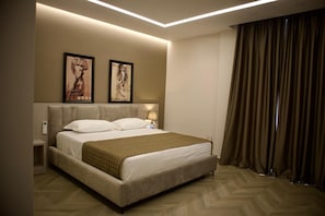 Ein Hotelzimmer mit Bett, Kopfteil, Nachttischen, Wandbild und Vorhang.