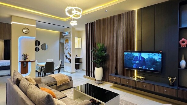 Una sala de estar moderna con un sofá, una mesa de centro, televisión y un área de comedor al fondo.