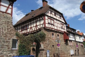 Ein traditionelles Fachwerkhäuschen mit Steinmauern, einem gut sichtbaren Eingang und einem kleinen Baum davor.