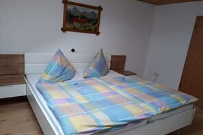 Ein Bett mit kariertem Überwurf, zwei Kissen, einem Holzkopfteil und einem Bild an der Wand.