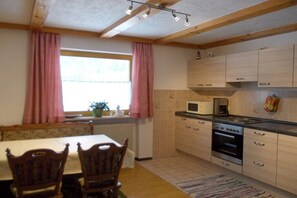 Eine Küche mit Holzschränken, einer Mikrowelle, einem Backofen und einem Esstisch mit Stühlen.