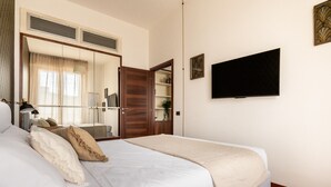 Een netjes ingerichte slaapkamer met een bed, een kast, een televisie en een spiegel.
