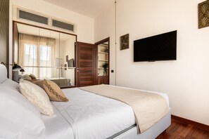 Ein ordentlich eingerichtetes Schlafzimmer mit Bett, Kleiderschrank, Fernseher und Spiegel.