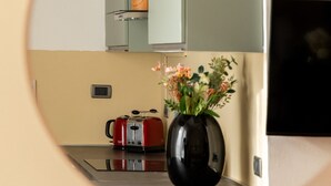 Een keuken met een ronde spiegel die een bloevas, een rode waterkoker en een magnetron weerspiegelt.