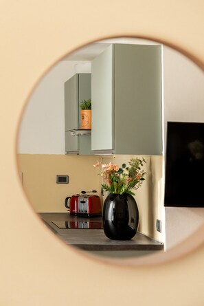 Eine Küche mit einem runden Spiegel, der eine Blumenvase, einen roten Wasserkocher und eine Mikrowelle reflektiert.