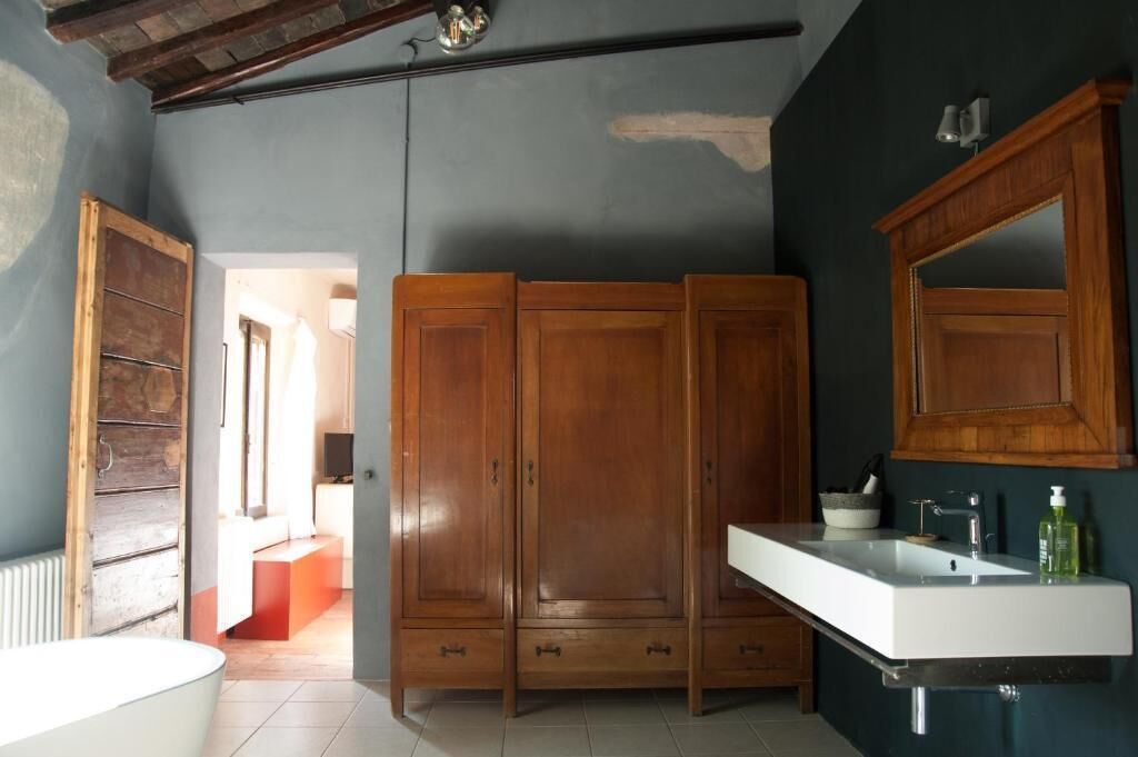 Un baño con lavamanos blanco, armarios de madera y un espejo.