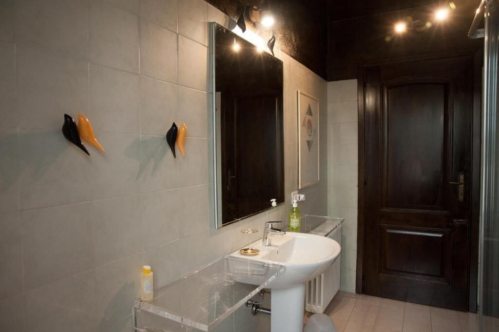 Een badkamer met een witte wastafel, een spiegel en een deur.