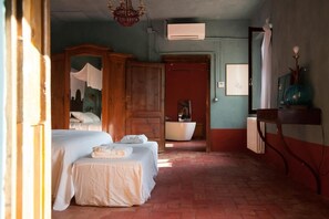 A room with a bed, a wooden wardrobe, a mirror, a radiator, and a bathroom visible through an open door. - Corte Mantovanella (Porto Mantovano)