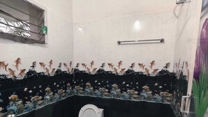 A bathroom with a toilet, a sink, a shower, and a decorative fish tank. - Aala Homestay (Palayankottai)