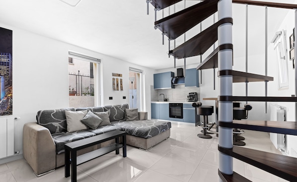 Una sala moderna con un sofá modular, una mesa de centro y una escalera.