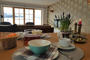 A dining table with a tea set, a bowl, a cup, and a candle holder. - "Kaiserwinkl" in the Chalet KAISER (Reit im Winkl)