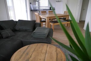 Ein Wohnzimmer mit einer Couch, einem Couchtisch und einem Essbereich mit Tisch und Stühlen.