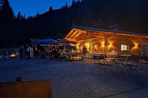 Un chalet rustique doté d’un coin repas, d’un espace extérieur aménagé et d’un foyer.