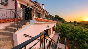 Un immeuble à plusieurs étages doté d’un balcon, d’un escalier extérieur et offrant une vue sur un vignoble.