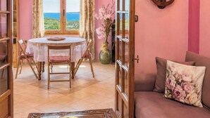 Une pièce comprenant une table à manger, des chaises, un canapé, une horloge et une vue sur la mer.