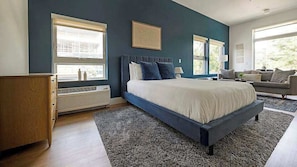 A bedroom with a bed, a dresser, a sofa, and a window. - Roami at Studio 135 (Denver)