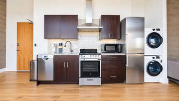 Une cuisine moderne dotée d’appareils électroménagers en acier inoxydable, de meubles de rangement en bois foncé et d’un four encastré.