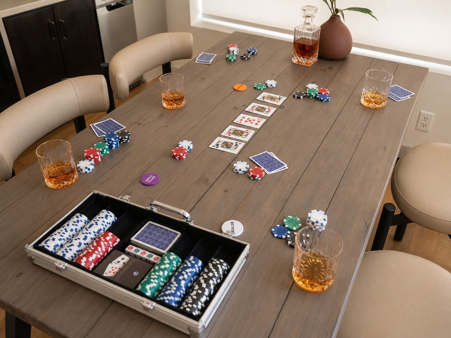 Una mesa de póker con fichas, cartas y vasos de whisky.