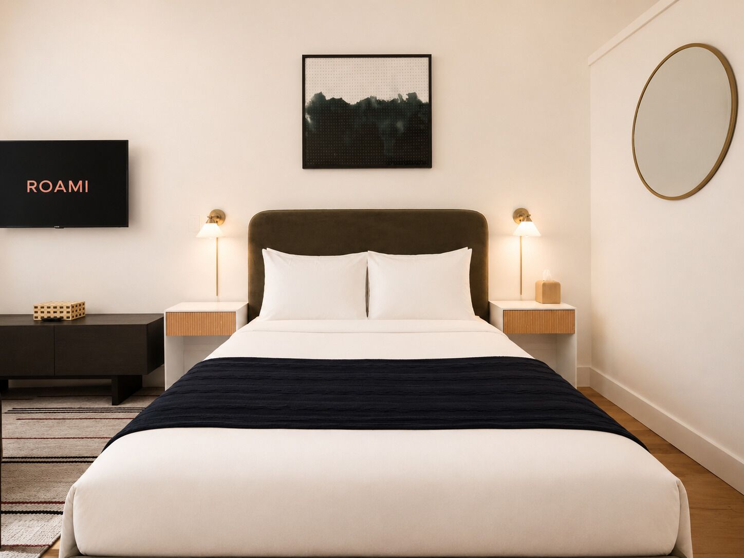 A neatly arranged hotel room with a bed, bedside tables, a TV, and a framed picture on the wall.