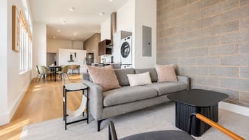 Een moderne woonkamer met een grijze bank, een klein rond tafeltje en een zwarte salontafel.