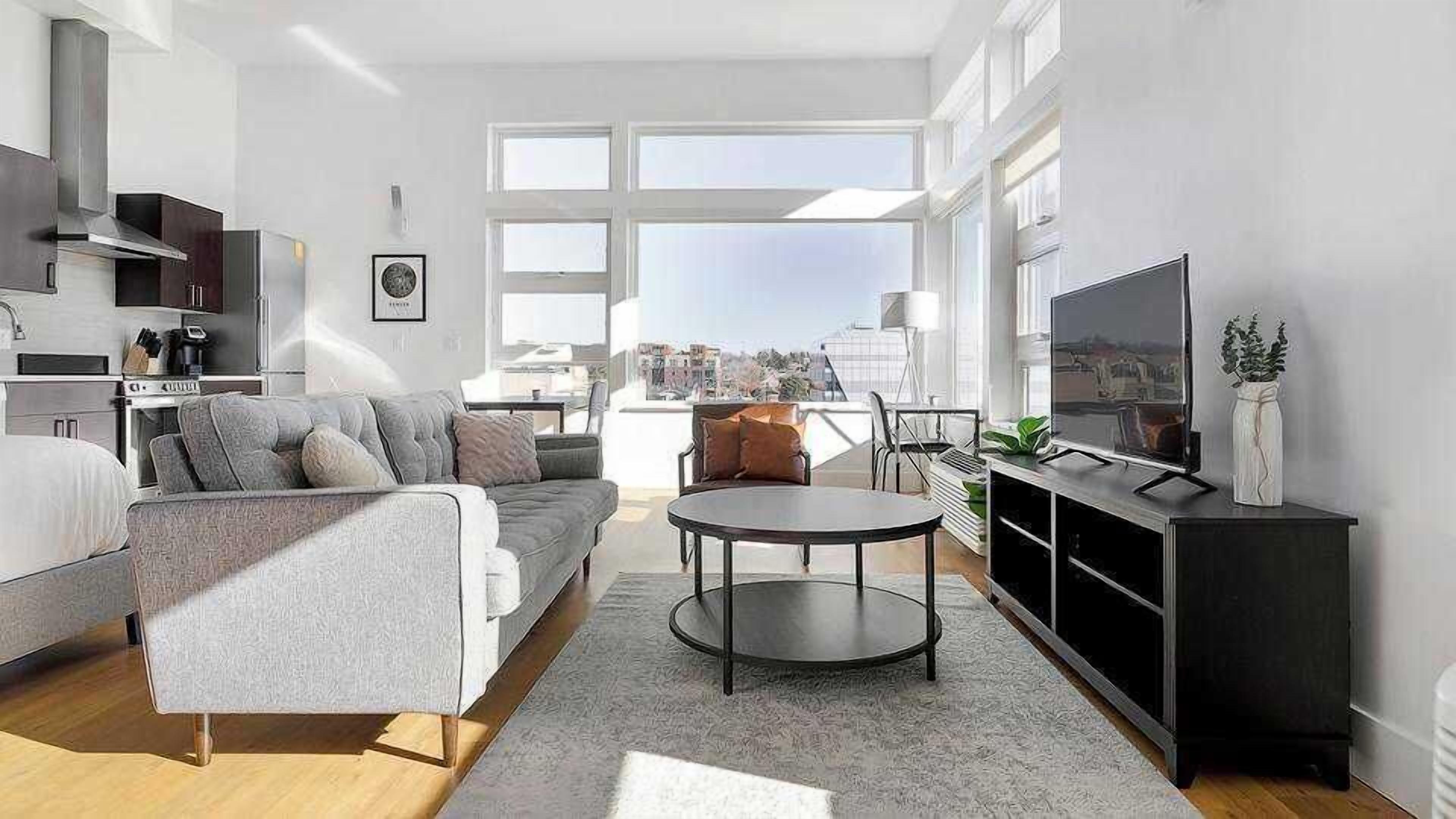 A modern living room with a sofa, coffee table, TV, and city view.