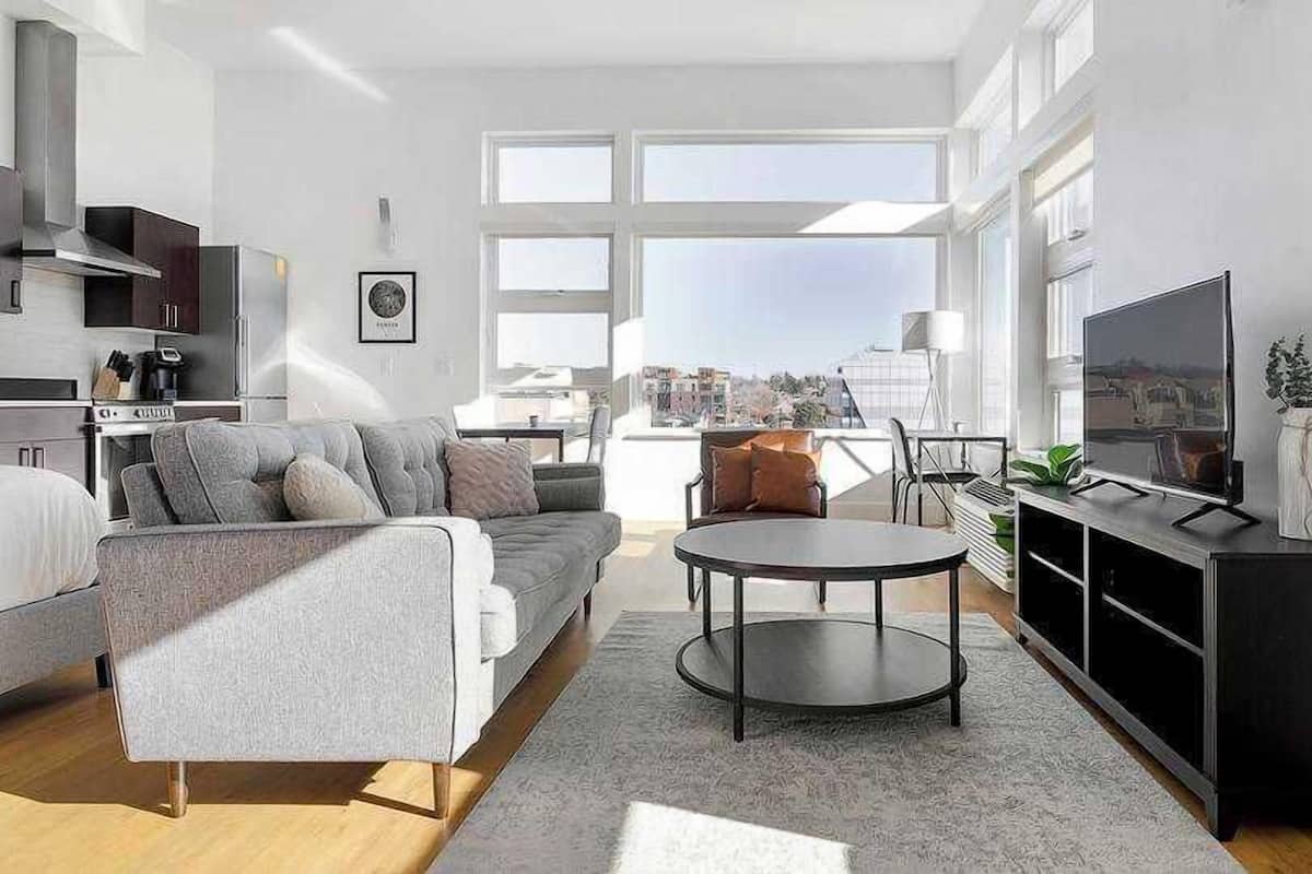 A modern living room with a sofa, coffee table, TV, and city view.