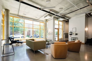 A modern interior with large windows, a seating area with sofas, and a visible outdoor view. - Roami at Studio 135 (Denver)