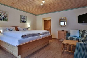 Ein Zimmer mit einem hölzernen Bett, einer Couch, einem kleinen Tisch und einem Spiegel.