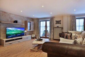 Ein modernes Wohnzimmer mit Flachbildfernseher, einer Couch, einem Couchtisch und einem Kamin.