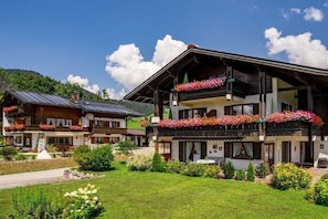 Ein traditionelles Chalet mit einem Blumen geschmückten Balkon, einem gepflegten Garten und freiem Blick auf die umliegende Landschaft.