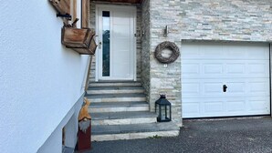 Ein Haus mit einer weißen Tür, Steinstufen, einem Laternen und einer Garagentür.