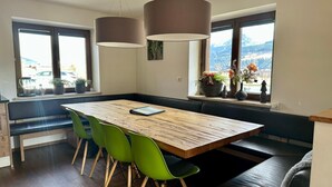 Eine moderne Küche mit einem Holztisch, grünen Stühlen und Pendelleuchten.