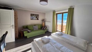Ein Hotelzimmer mit einem grünen Sofa, zwei Betten, einer Heizung und Blick ins Freie.