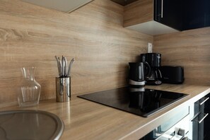 Eine moderne Küche mit Holzrückwand, einer Kaffeemaschine, einer Glasvase und einem Messerblock.