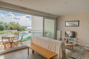 En moderne stue med balkon, fjernsyn og udsigt til pool.