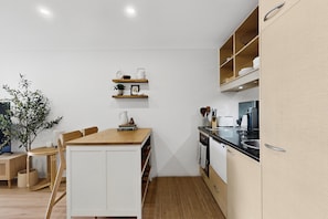 Eine moderne Küche mit weißen Schränken, Holzarbeitsplatten und einem Essbereich mit einem Holztisch und Stühlen.