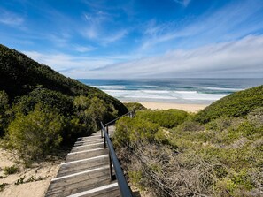 A wooden staircase leading to a beach with ocean views.