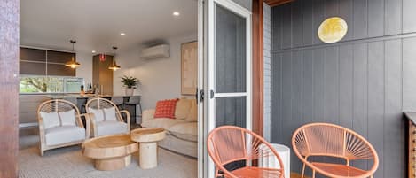 Un espacio habitable de concepto abierto con cocina, asientos con cojines y techo de madera.