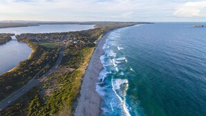 Luftaufnahme einer Küstenregion mit Strand, einer Straße und einer kleinen Siedlung.