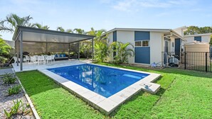 Une maison moderne dotée d’une piscine, d’un patio couvert et d’une cour clôturée.