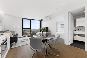 Eine moderne Wohnung mit Essbereich, Küche und großen Fenstern mit Blick auf die Stadt.