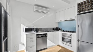 Eine moderne Küche mit weißen Schränken, einem Geschirrspüler, einem Backofen, einem Kühlschrank und einer eingebauten Mikrowelle.