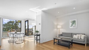 Ein modernes Wohnzimmer mit grauem Sofa, einem Couchtisch und einem Essbereich mit Glastisch und Stühlen.