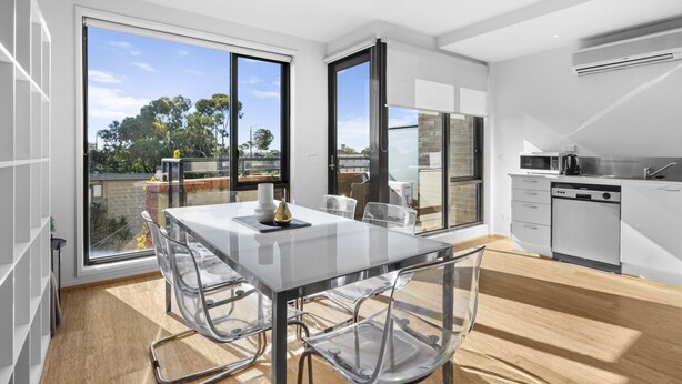 Eine moderne Küche mit Essbereich, großen Fenstern und Blick auf Bäume.